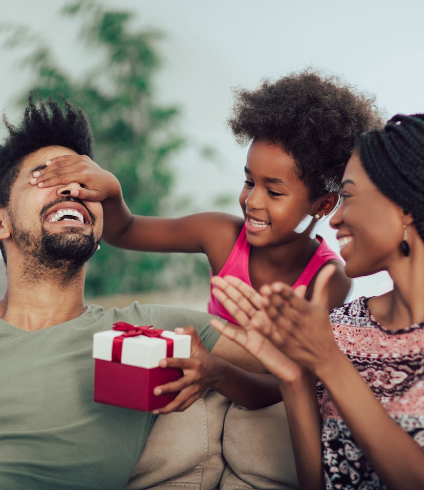 Happy black family at home. African american father, mother and child celebrating birthday, having f...