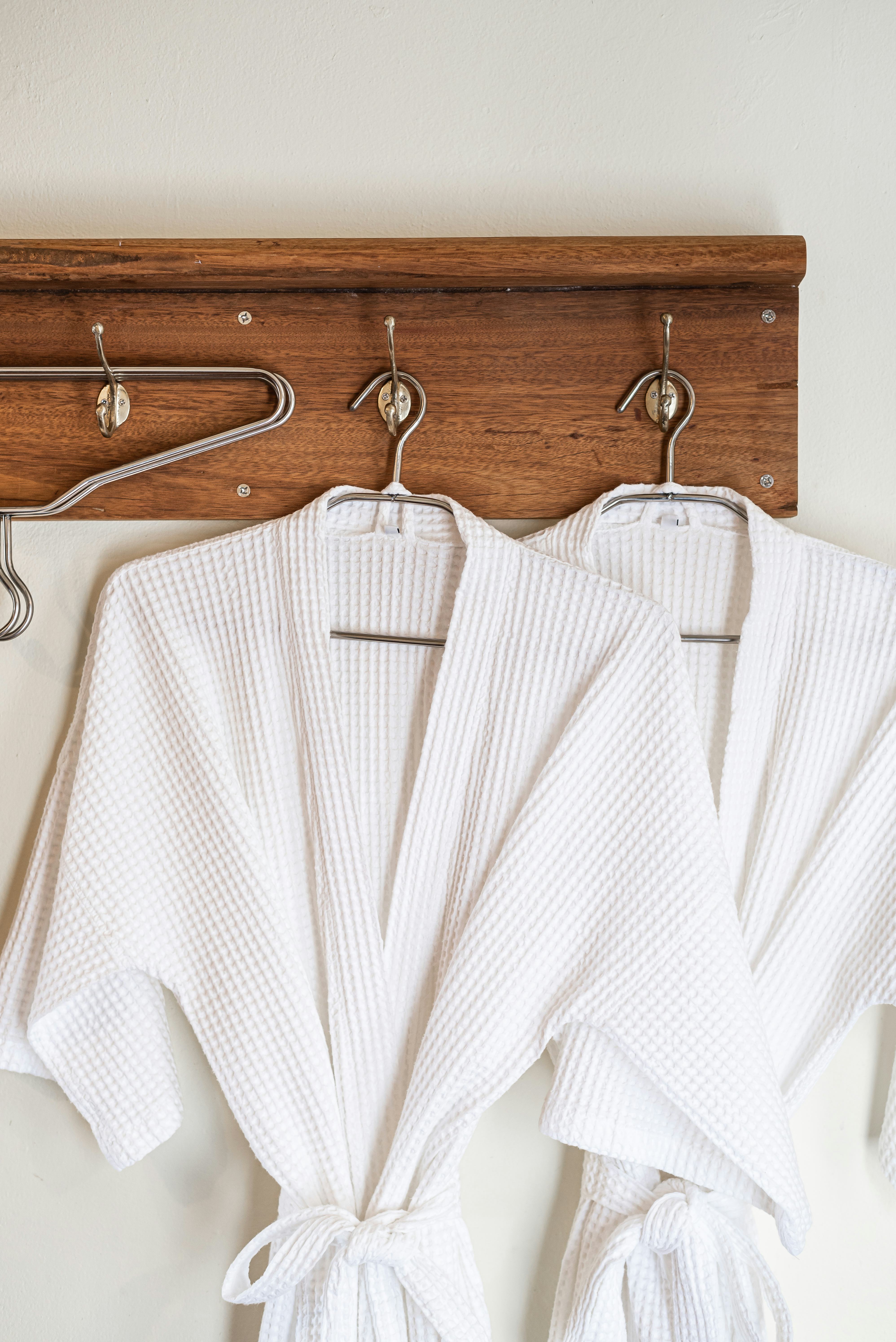 White bathrobes hanging on wooden hooks