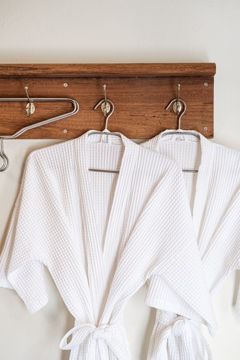 White bathrobes hanging on wooden hooks