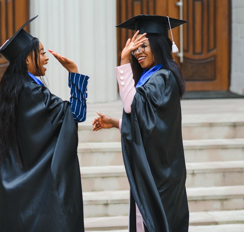 young graduates standing in front of university building on graduation day