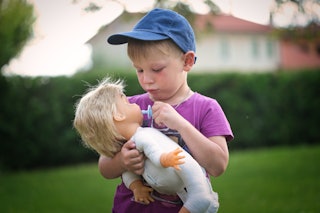 A little boy plays with a doll -- a recent study found that kids who play with dolls develop vital i...