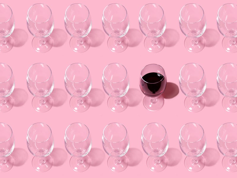 Glass pattern. Repeating empty wine glass on pink background.One glass filled with wine. Abstract ba...