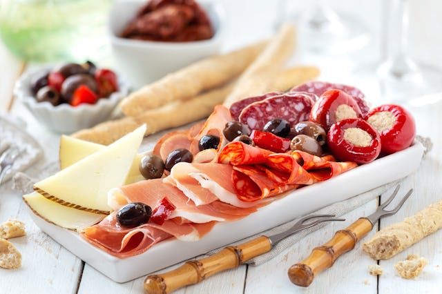 Delicious meat platter with cheese, spicy olives and stuffed cherry pepper served as an appetizer wi...