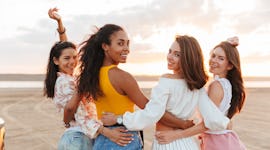 four women stroll on the beach as they each discuss how the 2022 new moon in gemini will affect them