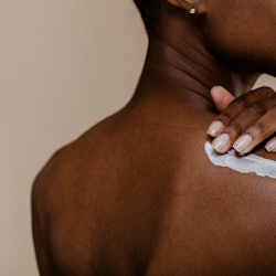 Black woman applying body cream