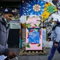 Pedestrians pass a sidewalk refrigerator stocked by various community support organizations to aid t...