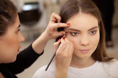 Cropped shot of a professional makeup artist working at her beauty studio, doing eyebrows of a femal...