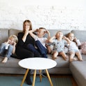 A mother with four small children on a sofa. A study shows that people with three or more children s...