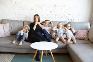 A mother with four small children on a sofa. A study shows that people with three or more children s...