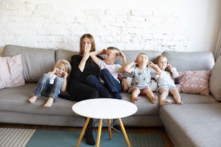 A mother with four small children on a sofa. A study shows that people with three or more children s...