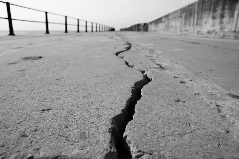 A large crack in concrete. Earthquake concept photo. This picture has selective focus. 