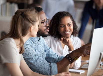 Diverse businesspeople working in shared office, focus on black american team leader sitting at desk...