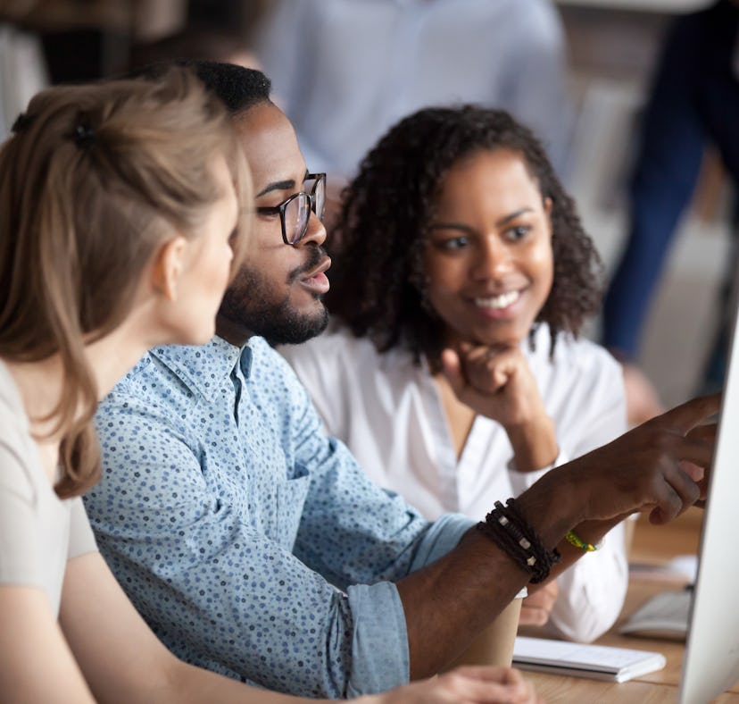 Diverse businesspeople working in shared office, focus on black american team leader sitting at desk...