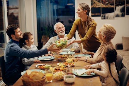 Happy multi-generation family enjoying in a lunch together at home. Focus is on young woman serving ...