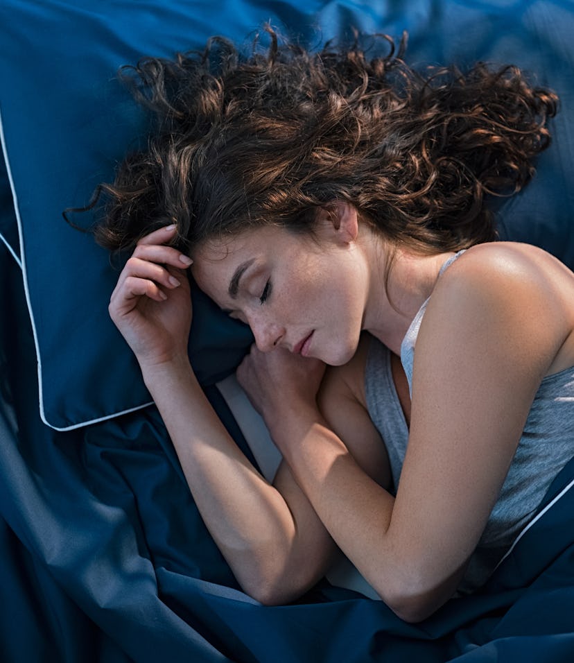 Top view of young woman sleeping on side in her bed at night. Beautiful girl sleeping profoundly and...