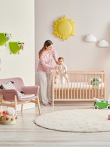 Baby and her mom in the room, decorative interior style with wooden cribbed pink chair toy and stair...