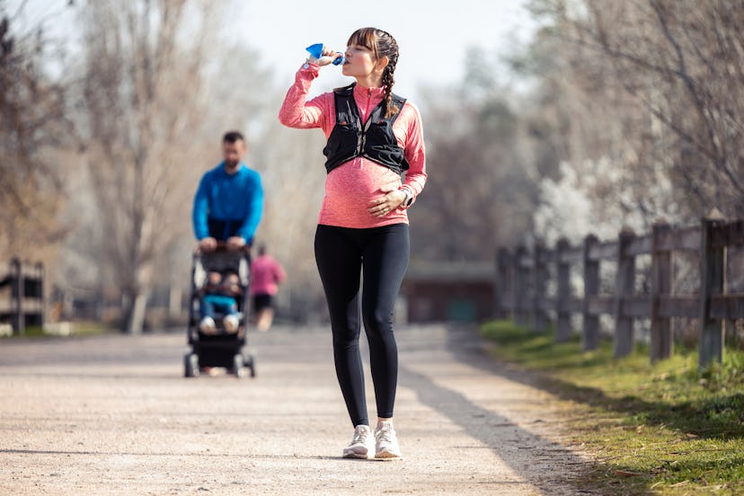 Shot of pregnant young woman drinking water in the park staying hydrated and training for a marathon...