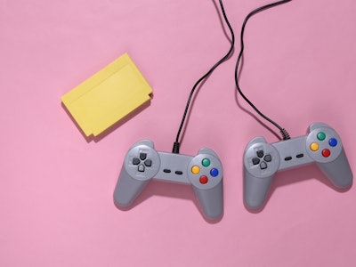 Retro video game cartridge and joysticks on pink bright background. Top view