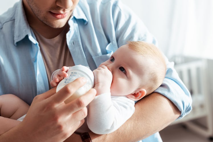 young father feeding baby formula in a bottle