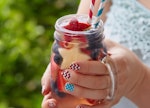 Patriotic drink cocktail with strawberry, blueberry and apple in woman's hands