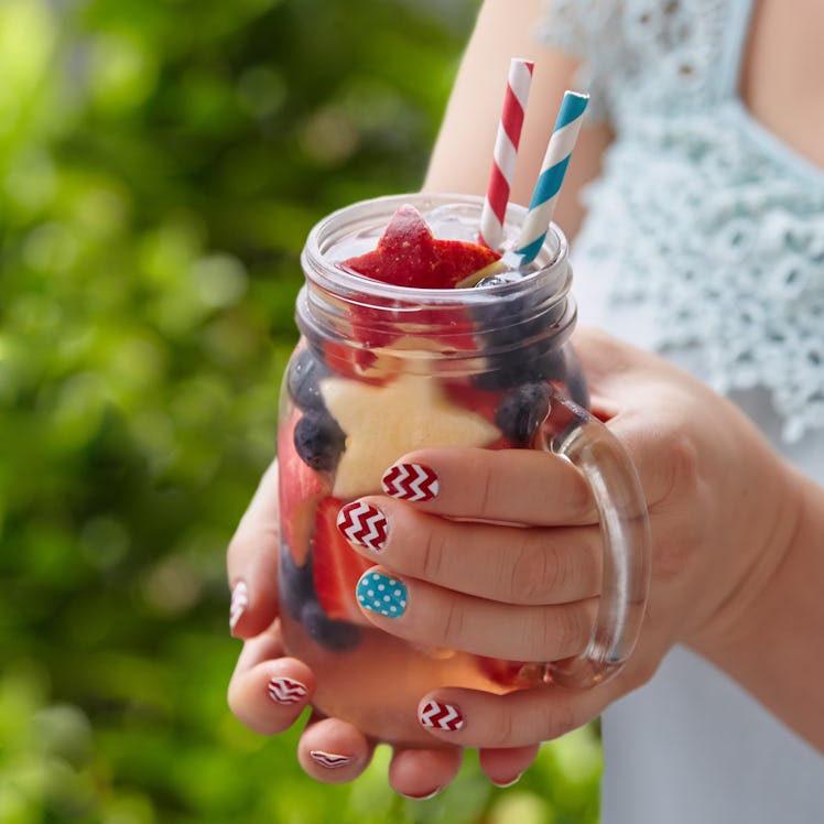 Patriotic drink cocktail with strawberry, blueberry and apple in woman's hands