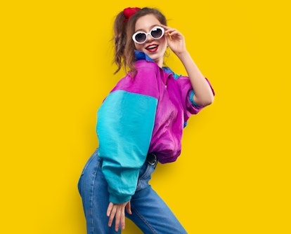 Cool teenager. Fashionable DJ girl in colorful trendy jacket and vintage retro sunglasses enjoys sty...