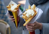 Belgian frites or french fries with mayonnaise in Brussels, Belgium. Female tourist holds two portio...