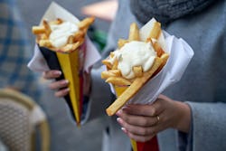 Belgian frites or french fries with mayonnaise in Brussels, Belgium. Female tourist holds two portio...