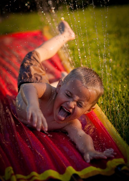A young boy finds relief from a hot summer day by playing on a Slip n Slide outside his omaha Nebras...
