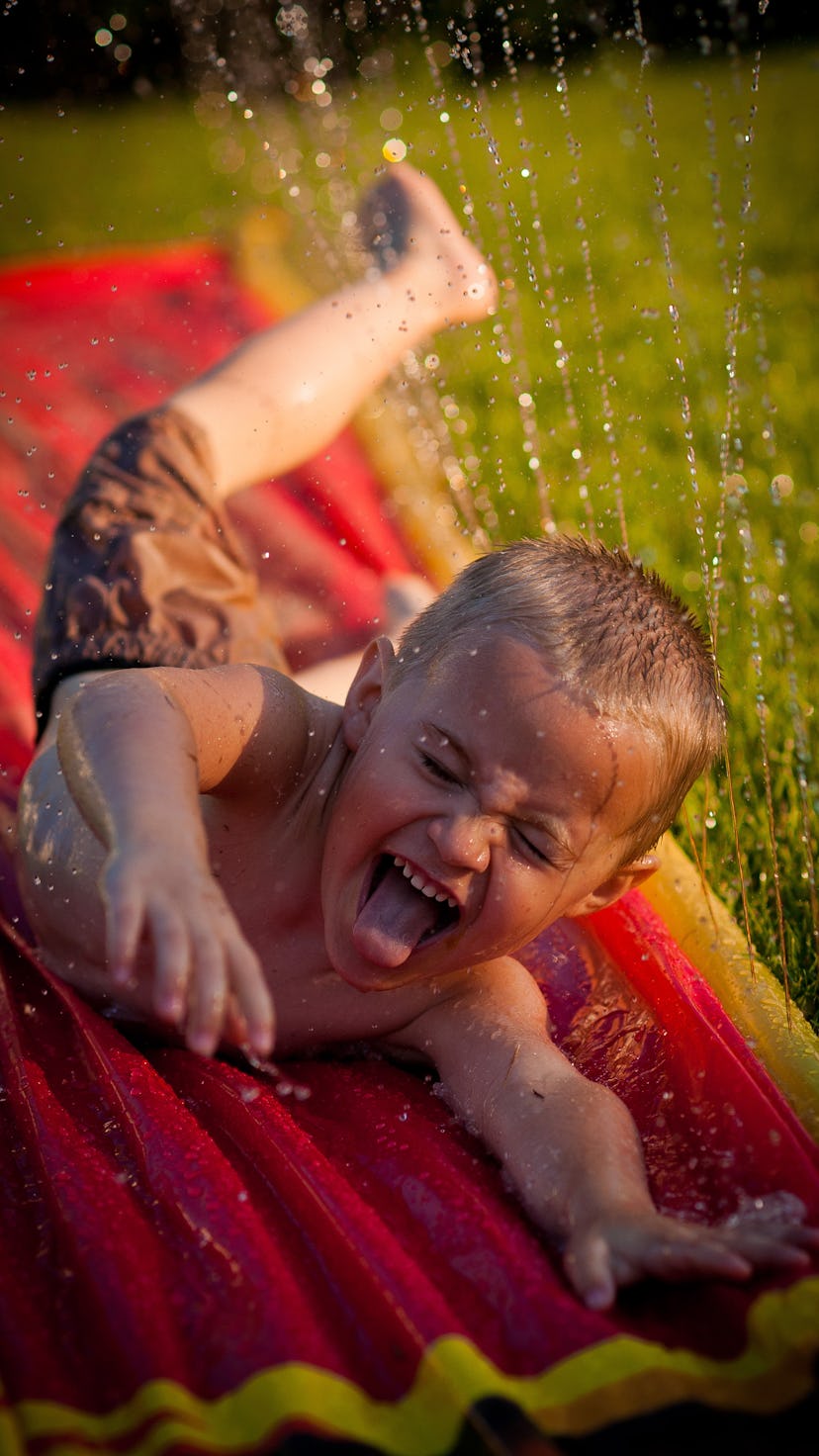 A kid going down a Slip n Slide on his stomach