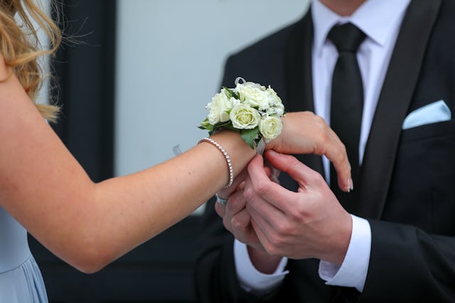 A corsage being placed on a teenagers wrist for a prom date.