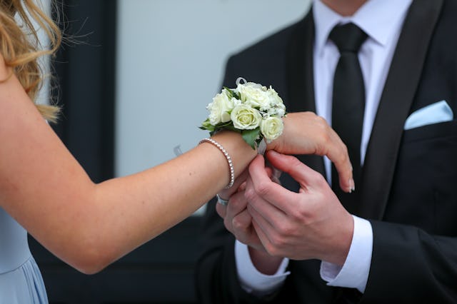 A corsage being placed on a teenagers wrist for a prom date.   