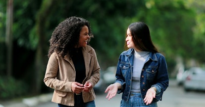Two diverse young women chatting in conversation outside