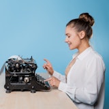 young woman writer at a typewriter, is inspired, is passionate about writing a text. Young brunette ...