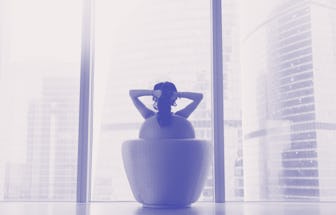 Young model sitting in armchair, hands crossed behind head, looking through panoramic glass wall at ...