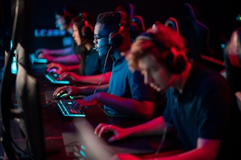 A multi-racial team of esports athletes conducts a training session before an online shooter tournam...