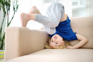 A little boy is standing on his head on a sofa. A study has found a relationship between kids' hyper...