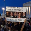 Nikki Tran of Washington, holds up a sign with pictures of Supreme Court Justices Clarence Thomas, B...