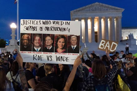 Nikki Tran of Washington, holds up a sign with pictures of Supreme Court Justices Clarence Thomas, B...