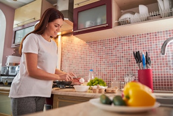 Una mujer adulta sola en la cocina rompe un huevo con un cuchillo pequeño