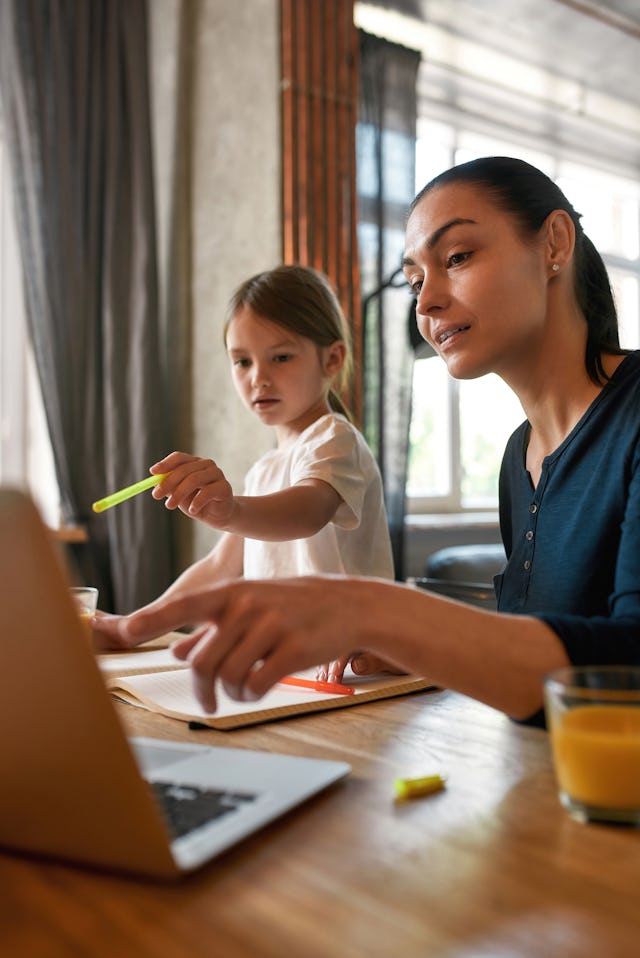 Little 7s girl child with young mom use computer study online on device at home. Caring Caucasian mo...