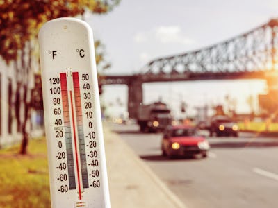 Thermometer in front of cars and traffic during heatwave in Montreal.