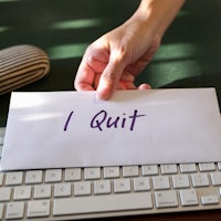 Hand handing resignation letter and put on top of keyboard