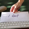 Hand handing resignation letter and put on top of keyboard