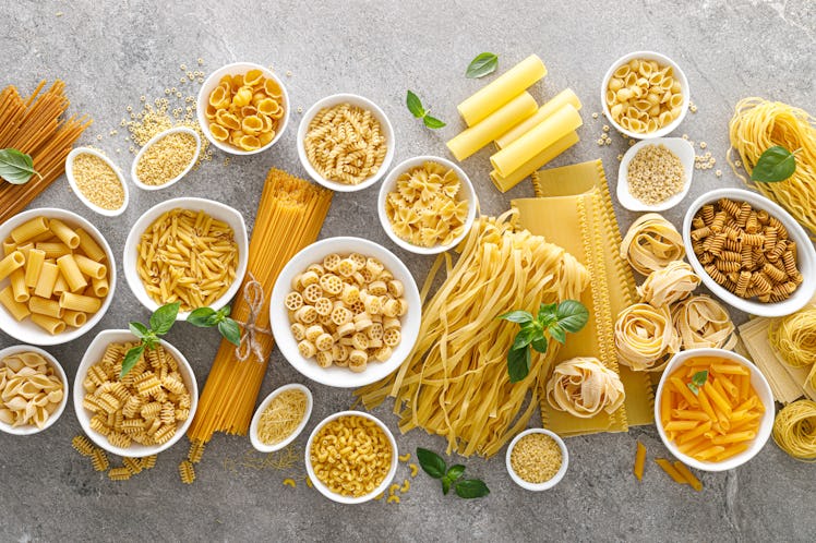 Pasta. Various kinds of uncooked pasta and noodles over stone background.