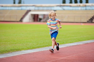 Child running in stadium. Kids run on outdoor track. Healthy sport activity for children. Little boy...