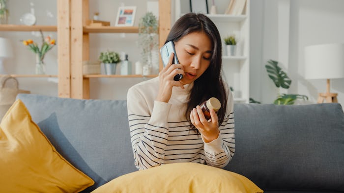 Woman sits on couch with phone, looking at a bottle of medicine, can i take tylenol while breastfeed...