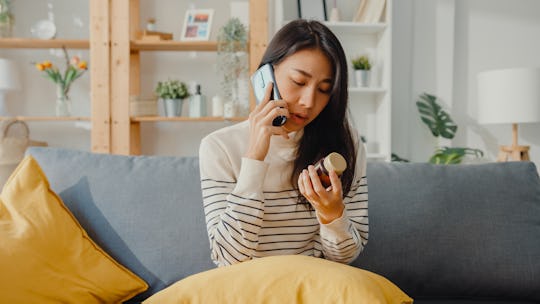 Woman sits on couch with phone, looking at a bottle of medicine, can i take tylenol while breastfeed...