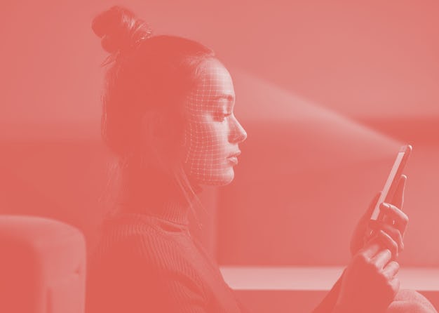 Female scans face using facial recognition system on smartphone for biometric identification. Future...