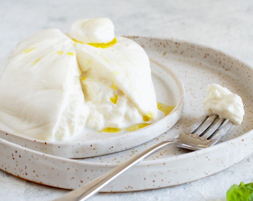 Italian burrata cheese on a plate with a fork and basil, is burrata safe to eat during pregnancy